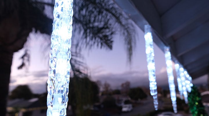 icicle christmas lights along a roofline at dusk